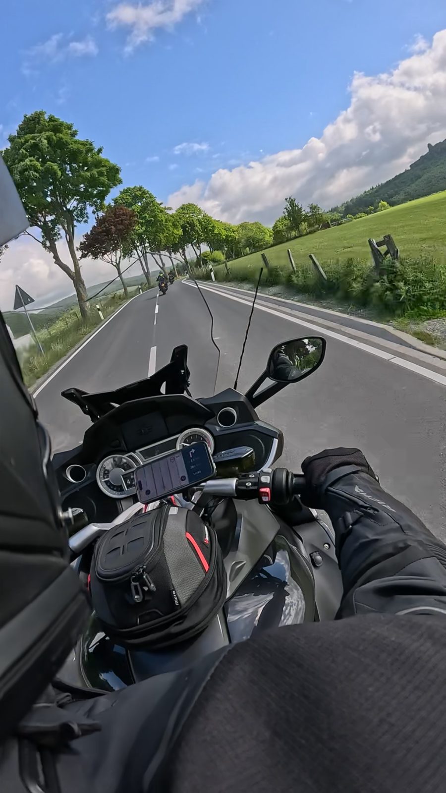 Uitzicht vanaf de motor, over het stuur heen, op een landweg met bomen