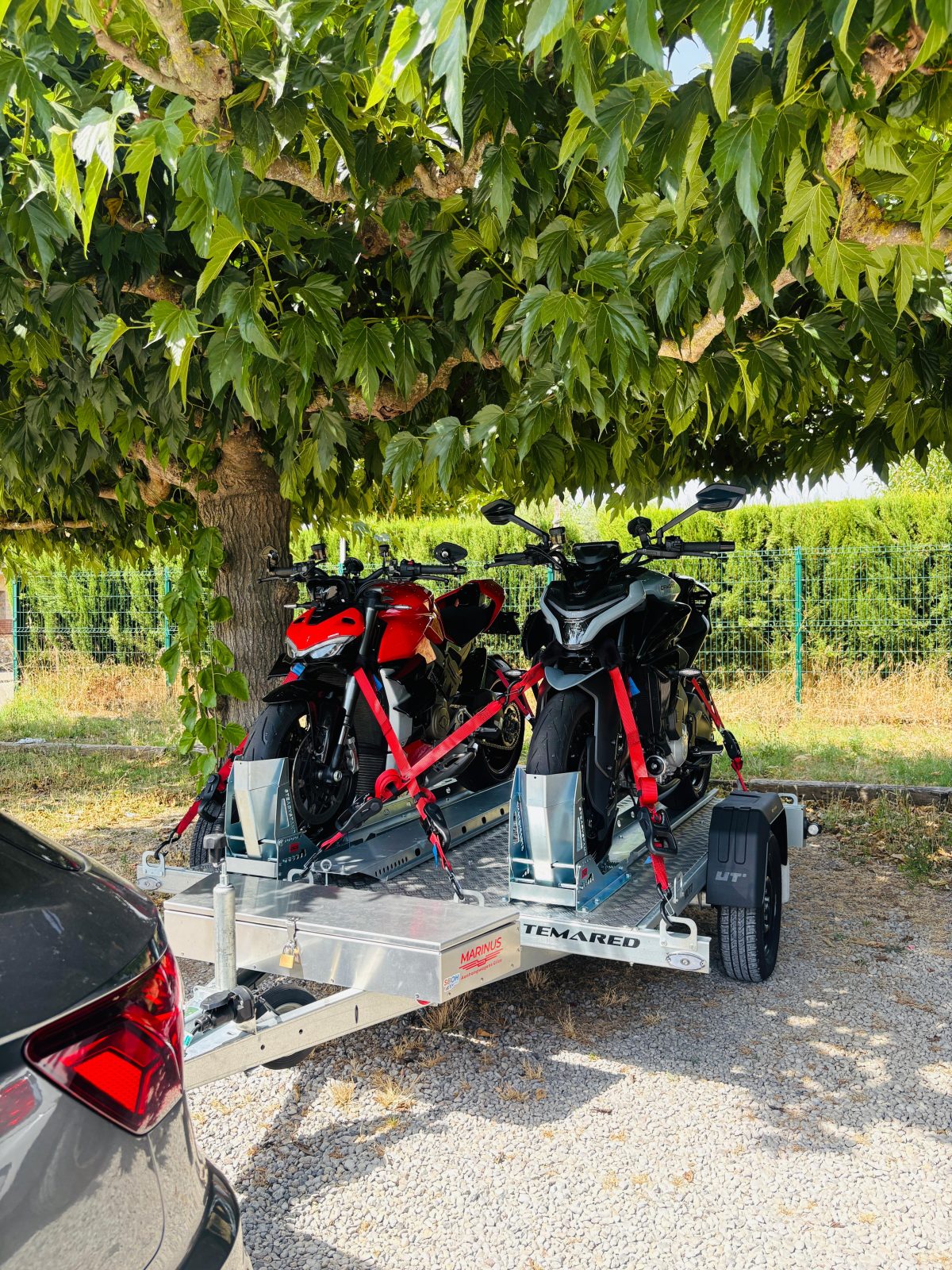 Twee motoren vastgezet op een motortrailer onder een boom, klaar voor vertrek